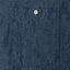 The front chest pocket of the dark denim work shirt  with a white button.