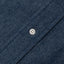 The closeup of the dark denim placket with a white button.