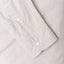 A grey shirt sleeve and cuff, two white buttons.