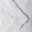A blue shirt sleeve and cuff, two white buttons.