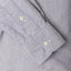 A navy shirt sleeve and cuff, two white buttons.