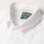 A closeup of the white button down collar, with white buttons and a green tag.