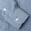 A blue shirt sleeve and cuff, two white buttons.