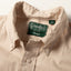 A close-up of the button down collar and a white button on the lined placket.