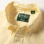 A close-up of the button down collar and a white button on the lined placket.