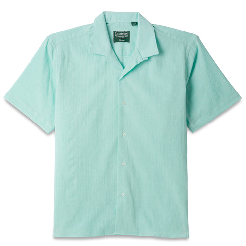 The Teal Dobby Stripe Chambray Camp Shirt, with short sleeves  and white buttons on the front.