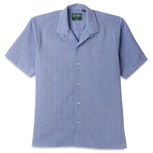 The Blue Dobby Stripe Chambray Camp Shirt, with short sleeves  and white buttons on the front.