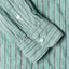 The barrel cuffs on the sleeve of the Green Awning Stripe shirt with white buttons.
