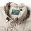 A close-up of the button down collar and a white button on the lined placket.