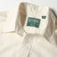 A close-up of the button free collar and a white button on the lined placket.