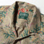 A closeup of the Tan Hawaiian Print Camp Shirt collar and the top button loop.