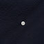The button on the placket on the the Navy Overdye Seersucker Camp Shirt.