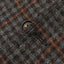 A closeup of the button hole on the grey checkered tweed simple jacket.