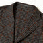 The lapel of the grey checkered tweed simple jacket.